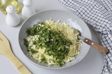 Add finely chopped dill and parsley, chopped garlic, salt and ground black pepper.
