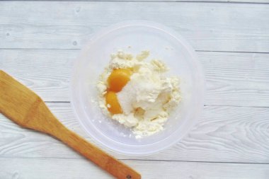 Put the curd in a separate bowl. Add egg yolks, sugar and a pinch of salt.