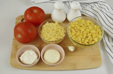 Prepare all the ingredients needed to make the Corn Cheese Tomato Salad. Wash the tomatoes, drain all the liquid from the corn. Peel the garlic, grate the cheese.