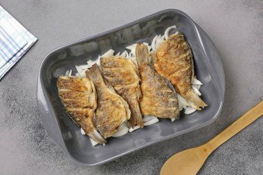 Chop the onion at random and place in an ovenproof dish. Place the fried carp on top.