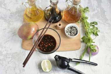 Start with a spicy dressing. In a small bowl, combine the grated ginger, brown sugar, half of the finely chopped chili, seeded and deseeded, the juice of half a lime, rice vinegar, soy sauce, and oyster sauces. Stir until the sugar is completely diss