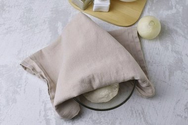 Hamuru yağlı bir kaseye koy ve hamuru havluyla ört..