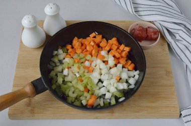 Sebzeleri soy ve küçük küp doğra: soğan, havuç, kereviz. Yumuşayana kadar sebze yağında kızart.