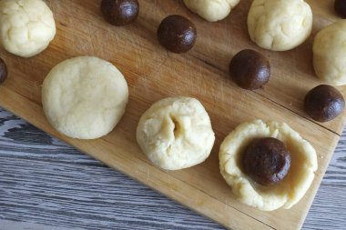 Kurabiye yapın. Hamuru pastanın içine koy. Tarih doldurma kısmını ortaya koy. Pastanın kenarlarını kaldır ki dolguyu kapatsınlar ve tamamen kapatsınlar. Kenarlarını dikkatlice bağla. Topu yuvarla. Avucunla bastır.