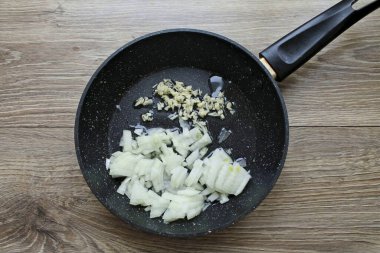 Soğanı doğra, soyun ve sarımsağı ince ince doğra. Sebze yağını kızartma tavasına dökün ve ısıtın, sebze ekleyin ve 6 dakika boyunca orta sıcaklıkta kızartın..