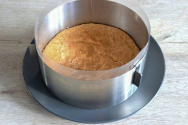 Soğumuş bisküviyi tekrar şekerleme halkasına koy, bir tabağa koy, kalıbın kenarlarını asetat bantla kapla..