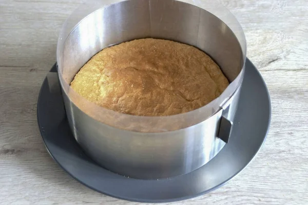 Soğumuş bisküviyi tekrar şekerleme halkasına koy, bir tabağa koy, kalıbın kenarlarını asetat bantla kapla..