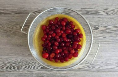 Kızılcıkları yıka ve eleğe koy. Böylece bardakta fazla nem olur..