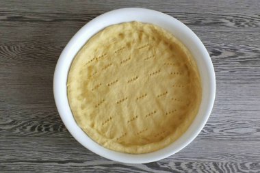 Hamuru forma dağıt. Kenarlarını ve altını aynı kalınlıkta tutarak eşit derecede pişiriyorlar. Çatalla işyerinin altını delin. Kalıbı hamurla birlikte 15 dakikalığına buzdolabına koy. Ondan sonra, fırına koy. 