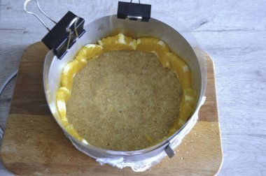 Buzdolabındaki kalıbı kaldır. Turuncu yarım halkaları pastanın kenarına yerleştir..