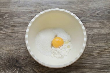 Bir kaseye şeker koy, kabartma tozu ile unu incele ve vanilya şekeri ekle. Yumurtayı protein ve sarıya böl, şimdilik proteini al ve sarısını bir kaseye koy. Her şeyi pürüzsüz olana kadar karıştır. Kütleleri birleştir ve pürüzsüz olana kadar vur.