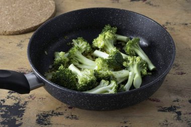 Brokoliyi infloresanlara böl. Tavaya ekle, her şeyi karıştır.