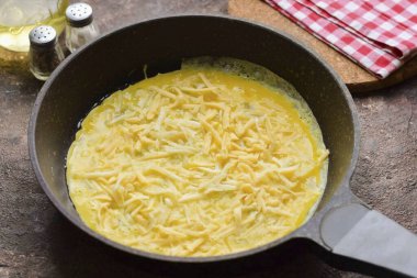 Tavayı ısıt, sebze yağını dök, sonra da yumurtayı dök. Sert peyniri rendele ve tavaya ekle..