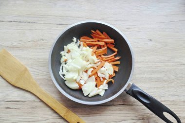 Havuç ve soğan soy ve yıka. İstenildiği gibi kes ve bir tavaya koy..