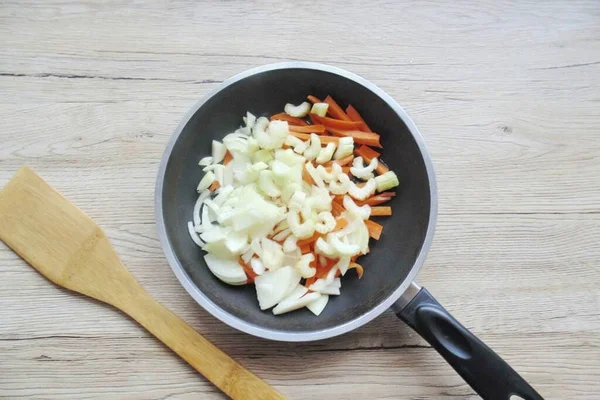 Wash and finely chop the stalk celery. Add to onions and carrots. Pour in sunflower oil and simmer vegetables for 10-12 minutes, stirring.