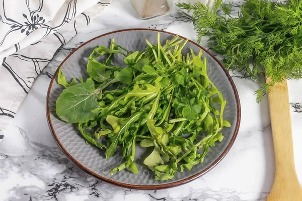 Rinse the arugula in water and cut the stems. Shake off excess moisture and place greens on a plate.