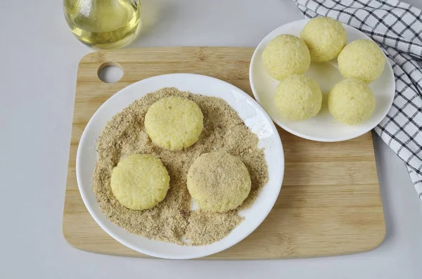 Divide the porridge into 8 parts. Roll into balls, flatten and roll in breadcrumbs.