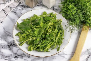 Roka 'yı durula ve yeşillikleri bir tabağa koy, saplarını kes..