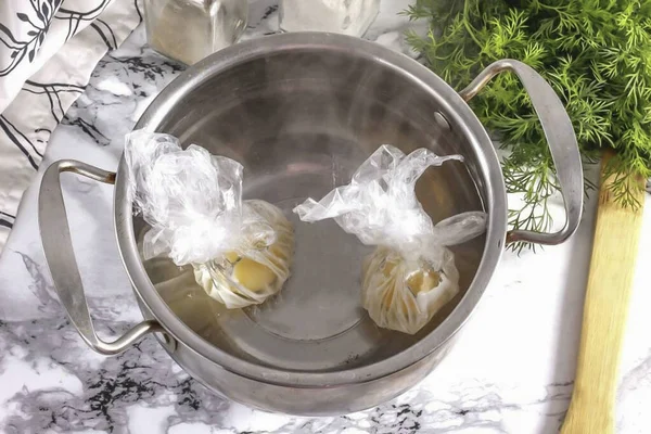 Boil water in a pot or ladle. Salt and pepper the eggs, gather the edges of the cling film and tie them up to make egg sacks. Immerse the bags for 2 minutes in slightly boiling water. The main thing is that the water should not boil, but simply tremb