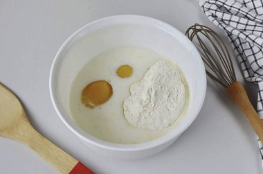 Sütle yumurtaları, bir tutam tuzu, unu ve şekeri birleştir..