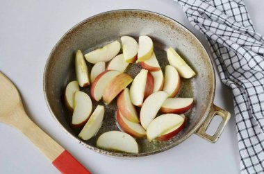 Elmaları yıka, çekirdekleri çıkar. Dilimlere böl, limon suyu serp. Kızartma tavasında erimiş yağ, elma ekle..