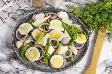 Tavuk yumurtalarını kabuklarından soy ve durula, dilimlere böl. Soğan dilimleri ve yeşillikleri bir tabağa koy. Peyniri üçgen şeklinde kes ve bir tabağa koy..