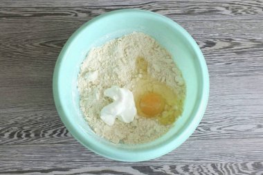 Yağlı un kırıntılarına ekşi krema ve yumurta ekle. Hamuru yoğur..
