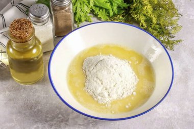 Çırpılmış yumurtanın içine su dök ve bir tutam tuz ekle. Tekrar vur. Sonra buğday unu ekle ve yavaşça karıştır, çok kalın bir hamur elde et, krep için olduğu gibi..