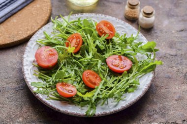 Kiraz domateslerini durula ve kurula, sonra ikiye böl ve roka üzerine salatayı koy..