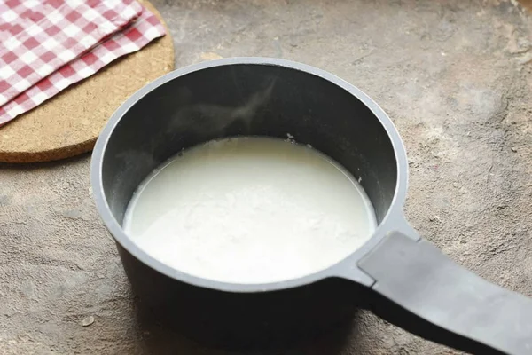 把牛奶和水倒入平底锅里 放上火 加一点盐 — 图库照片