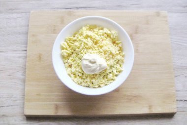 Haşlanmış yumurta, soğuk ve uzunlamasına ikiye bölünmüş. Yumurtanın sarısını dikkatlice çıkar, çatalla püre yap ve kaseye yengeç çubuğu ve otlu peynir ekle. Yumurtanın beyaz kısımlarını bir kenara bırak. Ayrıca kaseye mayonez ekle. Gerektiğinde tuz al.