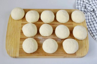 Hamuru 12 parçaya böl, her biri yaklaşık 65 gram. Her parçayı bir topa çevir..