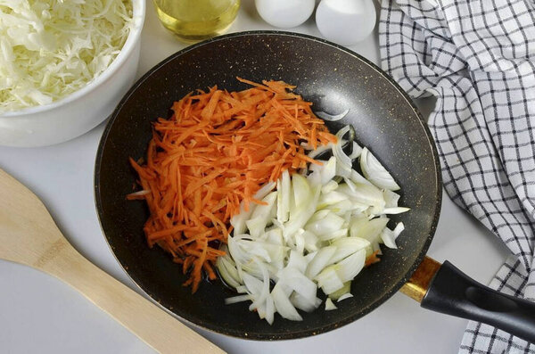 Peel the onions and carrots, grate the carrots on a coarse grater, and cut the onion thinly. Shred the cabbage. Heat 2 tablespoons of oil in a frying pan, add onions and carrots, fry for a few minutes.
