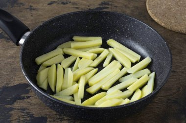 Patatesleri soy ve şeritleri kes. Altın kahverengiye kadar bir yanda patates kızartması.