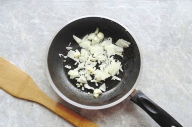 Soğan ve sarımsak soy, yıka, doğra ve tavaya koy..