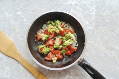 Brokoli tazeyse tuzlu suda kaynatın. Donmuş, çözülmüş, yıkanmış. Çiçeklere ayrılın ve diğer sebzelerle birlikte tavaya koyun. Tuz, biber. 2-3 dakika daha kaynat..