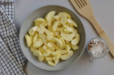 Hamur soğurken, elmaları hazırlayın: soyun, çekirdekleri çıkarın, dilimlere ayırın, limon suyu serpin, elmalar koyulaşmasın diye karıştırın. Ayrı bir kabın içinde, şeker, tarçın ve nişastayı birleştirin..