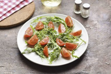 Roka 'yı durula ve kurula. Roka 'yı bir tabağa aktarın. Kiraz domateslerini durula ve ikiye böl. Domatesleri roka ile birlikte kaseye ekle..