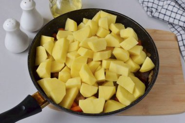 Patatesleri soy ve kes, et ve sebze ekle, birkaç dakika kızart..