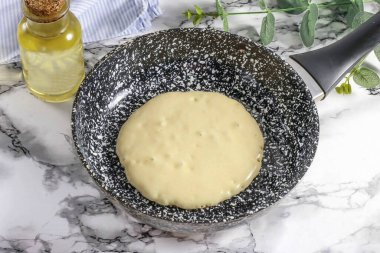 Tavayı önceden ısıt ve altını ilk kez sebze yağıyla yağla. Tavanın ortasına 2 tbsp dök. Sıcaklığı orta seviyeye düşürün. Yüzeyde büyük kabarcıklar görünene kadar krep pişir.