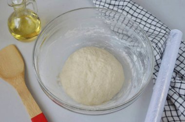 Un tamamen nemlendiğinde, masaüstüne gidin, elastik bir çörek oluşana kadar hamuru yoğurun. Genelde 5-6 dakikadan fazla sürmez. Mangırı kaseye geri koy, streç filmle üstünü ört ve 1,5 saatliğine sıcak bir yere koy..