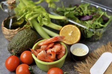 Avokado Karides Kereviz Salatası yapmak için gereken tüm malzemeleri hazırlayın. Karidesleri eritin, kereviz, domates ve salata karışımını akan suyun altında yıkayın..