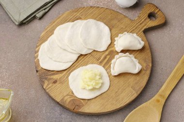 Sonra her parçayı daire şeklinde yuvarla, boşluğu dolguyla doldur ve uygun bir şekilde hamur köftesi oluştur..