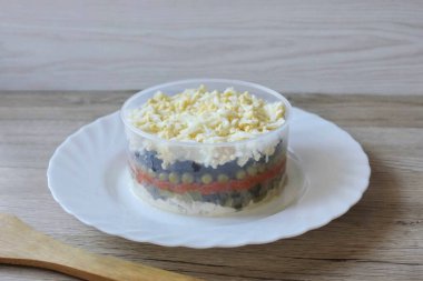 Yemek yüzüğünü bir tabağa koy ve malzemeleri katman katman ayır. İlk katman tavuk, sonra salatalık, havuç, konserve bezelye, fındıklı kuru erik ve yumurta. Her katmanı mayonezle yağlamayı unutma..