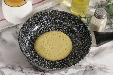 Tavayı ocakta ısıt ve ilk kez sebze yağıyla yağla. 2 tbp doldur. Tavanın ortasına vurun ve ısıyı orta seviyeye düşürün. Hamurun yüzeyinde kabarcıklar oluşana ve patlamaya başlayana kadar bekle.