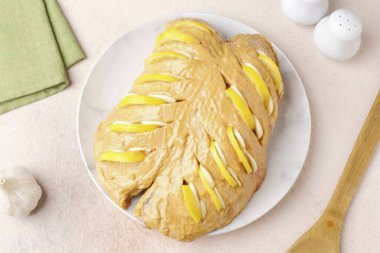 Sonra her kesiğe limon dilimleri ve doğranmış sarımsak ekleyin..