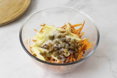 Havuçlara elma, havuç, kuru üzüm ve şeker ekle. Her şeyi karıştır. Salatanın suyunu biraz salgılamasına izin vermek için 10-15 dakika buzdolabı doldur. Servis etmeden önce salataya fındık serp..