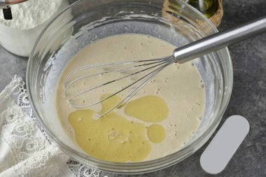 Biraz süt ekleyin ve pürüzsüz olana kadar çırpın. Yağı dök ve hamuru son kez döv. Pişirmeden önce hamuru 10 dakika dinlendir..