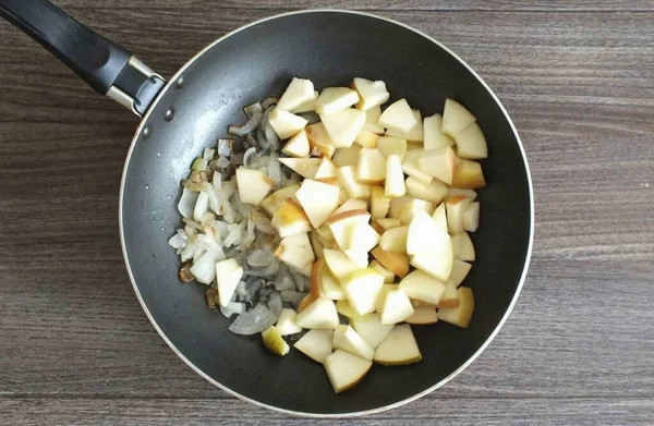 프라이팬에 기름을 가열하고 잘게썬 양파를 반쯤익을 때까지 볶는다 조각으로 사과를 — 스톡 사진