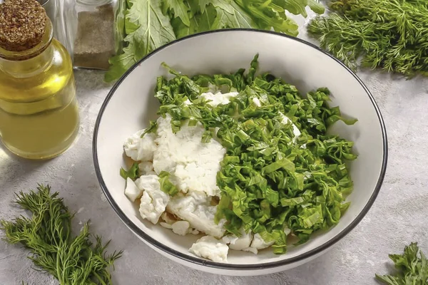 Süzme peyniri derin bir kaba koy. Roka yapraklarını durula ve saplarını kes. Yeşillikleri şeritler halinde kes ve süzme peynirli bir kabın içine koy..